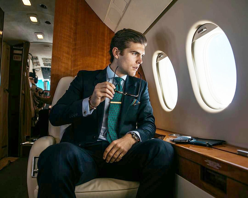 Gentleman travelling in an executive private jet dressed in a suit, wearing a signet ring