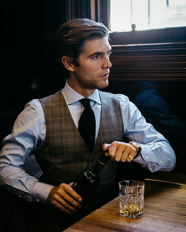 Gentleman wearing a shirt and waistcoat, pouring a whisky wearing a signet ring