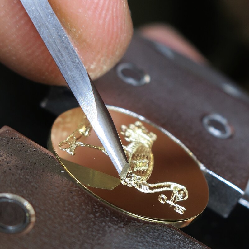 Hand engraving a Crest on a yellow gold cufflink