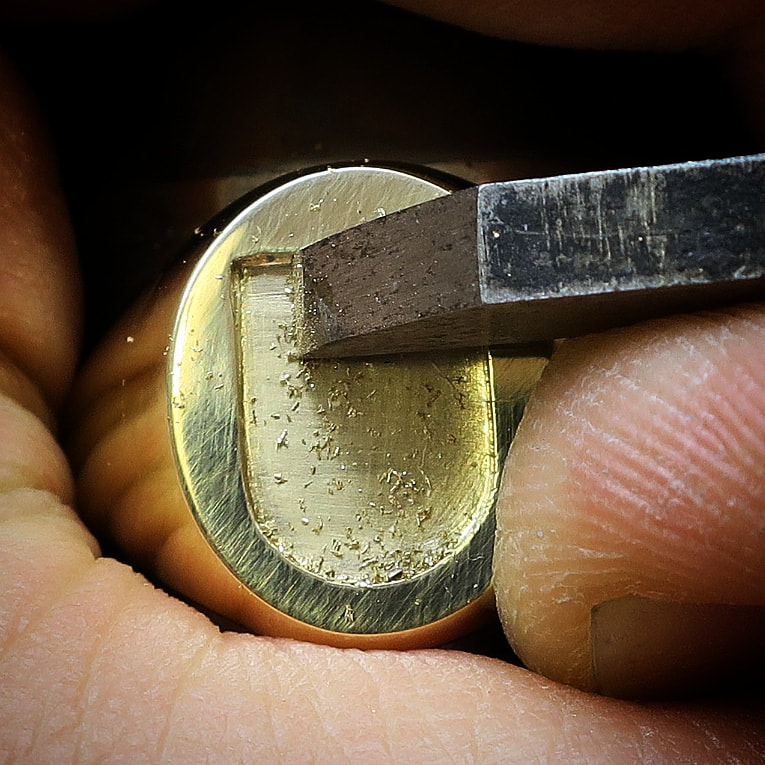 Removing the background for a seal engraved shield by hand with a graver, on a yellow gold signet ring